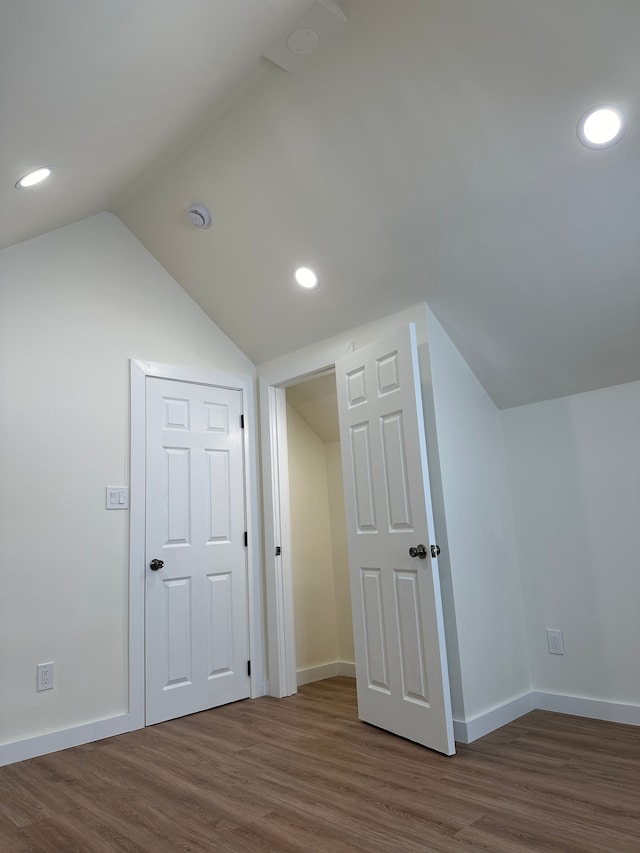 additional living space with recessed lighting, vaulted ceiling, baseboards, and wood finished floors