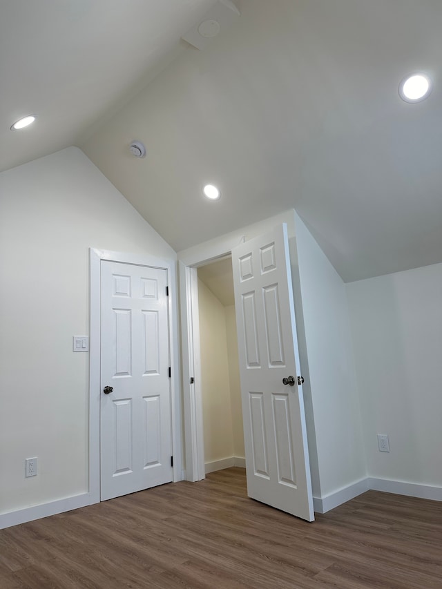 additional living space with baseboards, vaulted ceiling, wood finished floors, and recessed lighting
