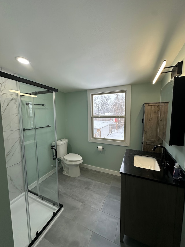 full bath featuring a stall shower, toilet, vanity, and baseboards