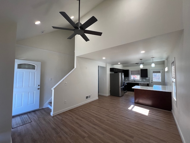 unfurnished living room featuring stairway, dark wood-style floors, baseboards, visible vents, and ceiling fan