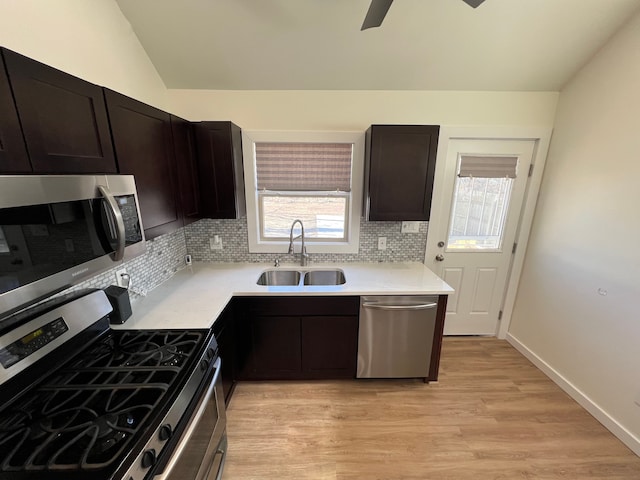 kitchen with a sink, tasteful backsplash, light wood-style floors, and appliances with stainless steel finishes