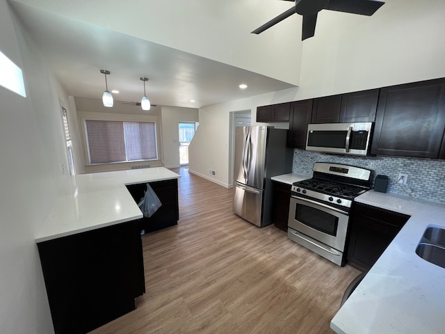 kitchen featuring a ceiling fan, appliances with stainless steel finishes, light wood-style floors, dark cabinets, and backsplash