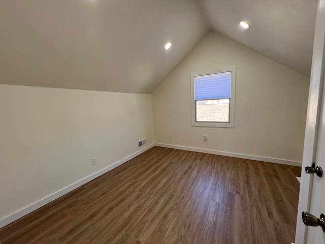 bonus room featuring baseboards, visible vents, vaulted ceiling, and wood finished floors