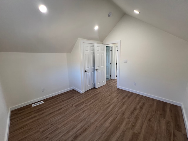 additional living space with dark wood finished floors, baseboards, visible vents, and vaulted ceiling