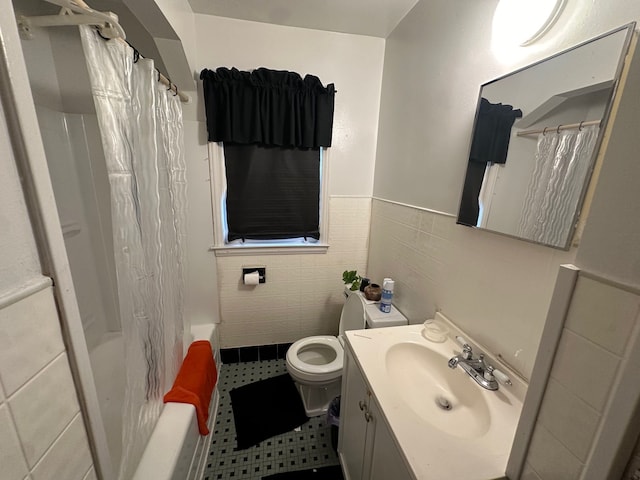 bathroom with wainscoting, toilet, tile patterned flooring, vanity, and tile walls