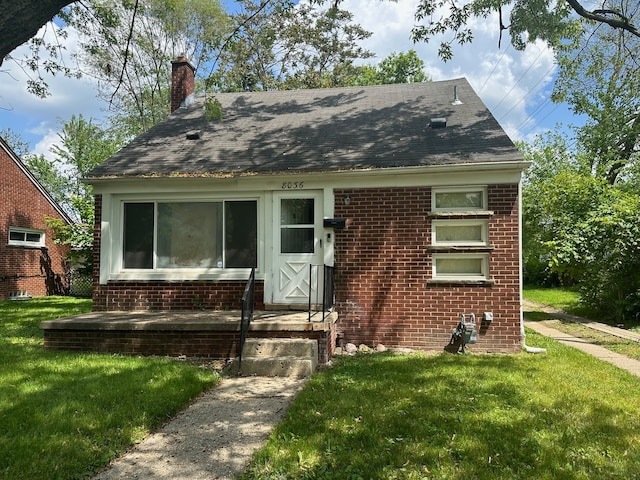 view of front of property with brick siding, a chimney, and a front lawn