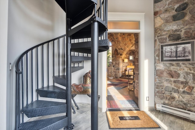 stairs featuring baseboard heating and wood finished floors