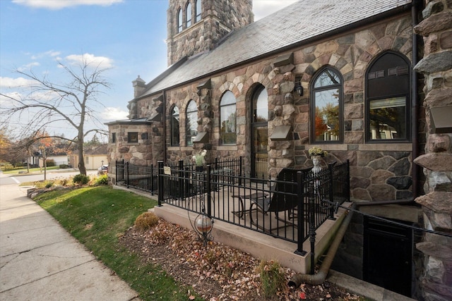 exterior space featuring a high end roof, stone siding, fence, and a chimney