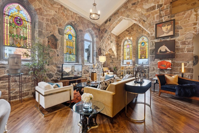 living area with wood-type flooring, high vaulted ceiling, and a notable chandelier