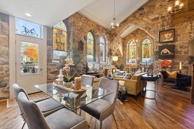 dining room featuring high vaulted ceiling, arched walkways, a notable chandelier, and wood finished floors