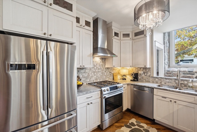 kitchen featuring backsplash, appliances with stainless steel finishes, a sink, light stone countertops, and wall chimney exhaust hood