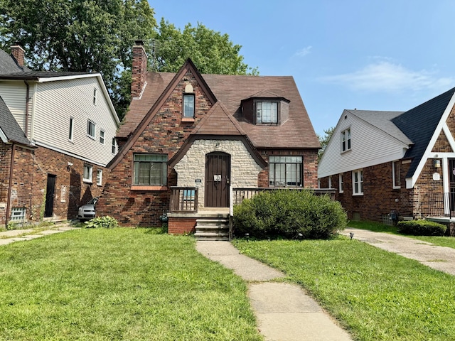 tudor house featuring a front lawn and brick siding