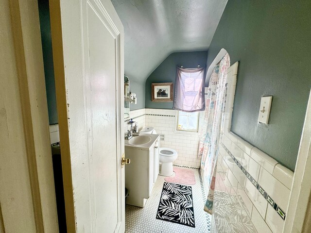 full bathroom featuring a wainscoted wall, tile walls, toilet, vanity, and tile patterned flooring