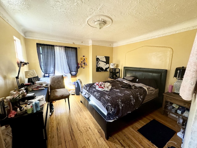 bedroom featuring hardwood / wood-style flooring, ornamental molding, and a textured ceiling