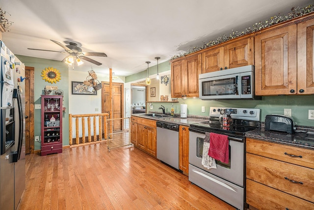 kitchen featuring brown cabinets, light wood finished floors, stainless steel appliances, and a sink