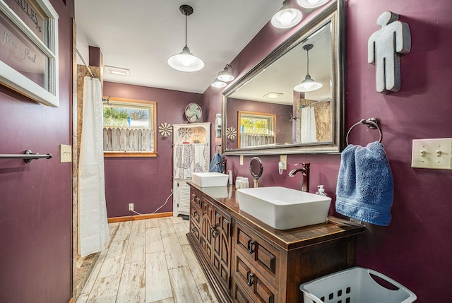 full bathroom featuring double vanity, baseboards, a sink, and wood finished floors