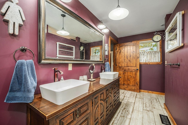 bathroom featuring double vanity, visible vents, a sink, and wood finished floors