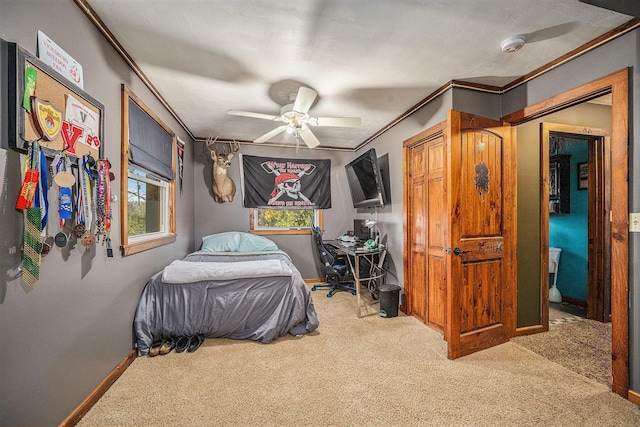 bedroom with a ceiling fan, carpet flooring, crown molding, and baseboards