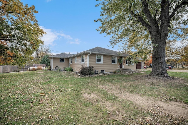 rear view of house featuring fence and a yard