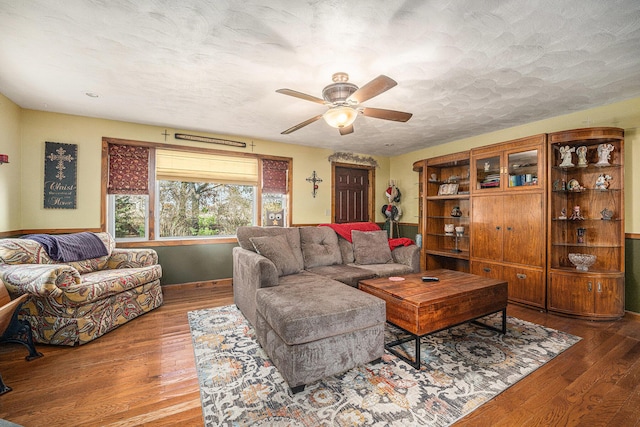 living room featuring ceiling fan, a textured ceiling, and wood finished floors