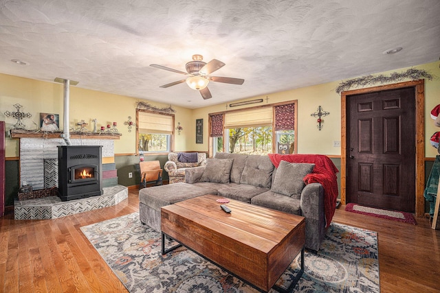 living area with ceiling fan, a textured ceiling, and wood finished floors