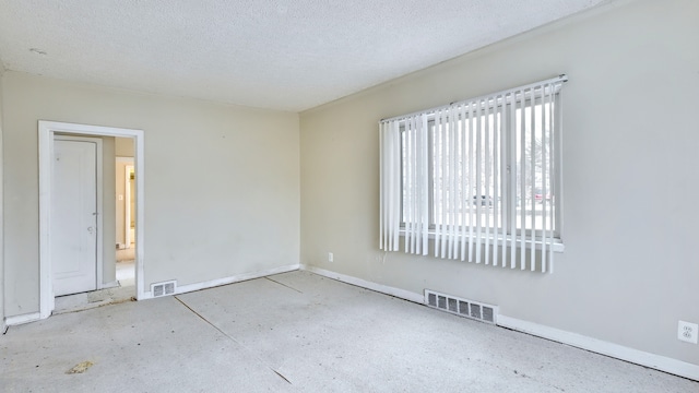 unfurnished room with visible vents, a textured ceiling, and baseboards