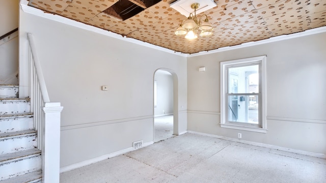 empty room with arched walkways, ornamental molding, and a chandelier