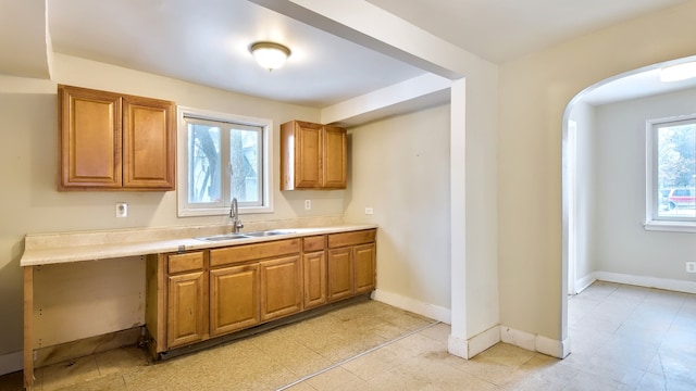 kitchen with light countertops, brown cabinets, a sink, and baseboards