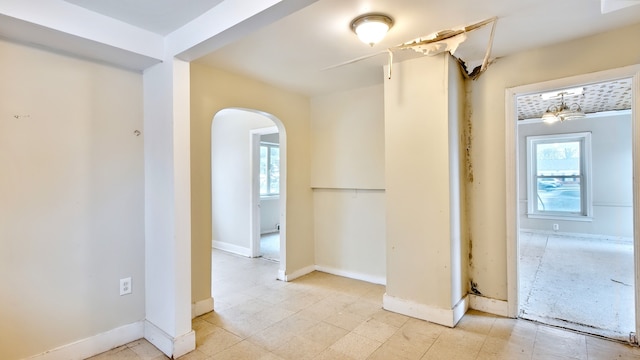 hallway featuring baseboards and arched walkways