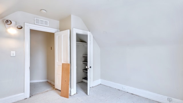 unfurnished bedroom with lofted ceiling, a closet, visible vents, and baseboards