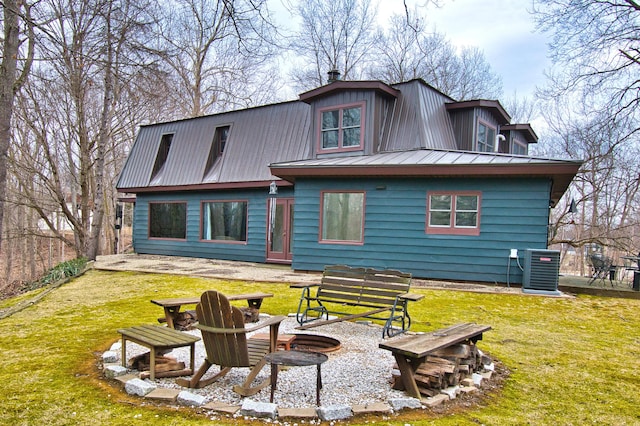 rear view of house with metal roof, a yard, an outdoor fire pit, and central AC