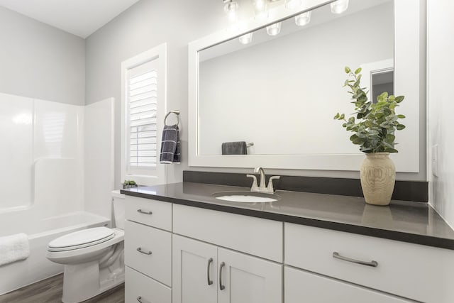 bathroom with toilet, shower / bathing tub combination, wood finished floors, and vanity