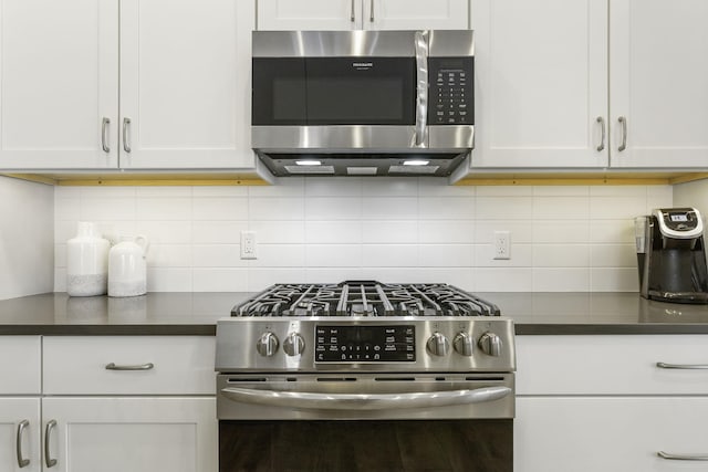 kitchen with stainless steel appliances, dark countertops, white cabinets, and tasteful backsplash