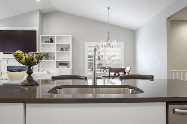 kitchen with lofted ceiling, dark countertops, a sink, and decorative light fixtures