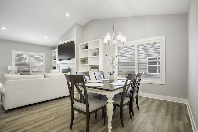 dining room with a fireplace, baseboards, vaulted ceiling, and wood finished floors