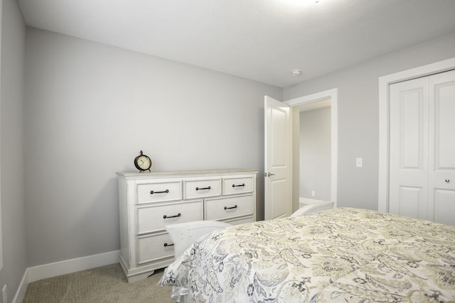 bedroom with baseboards, a closet, and light colored carpet