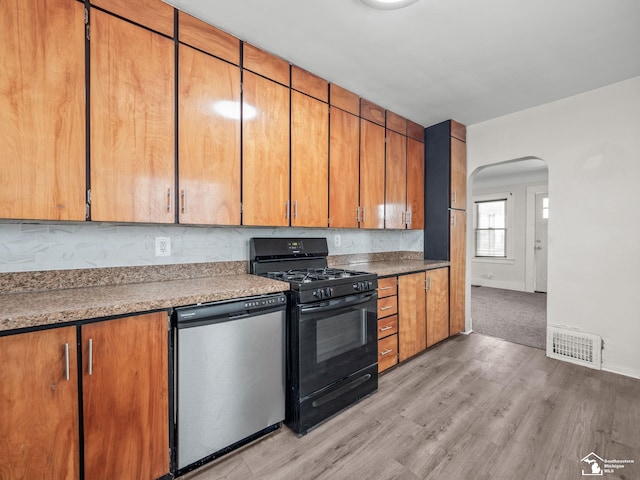 kitchen with visible vents, arched walkways, dishwasher, light wood-style flooring, and gas stove