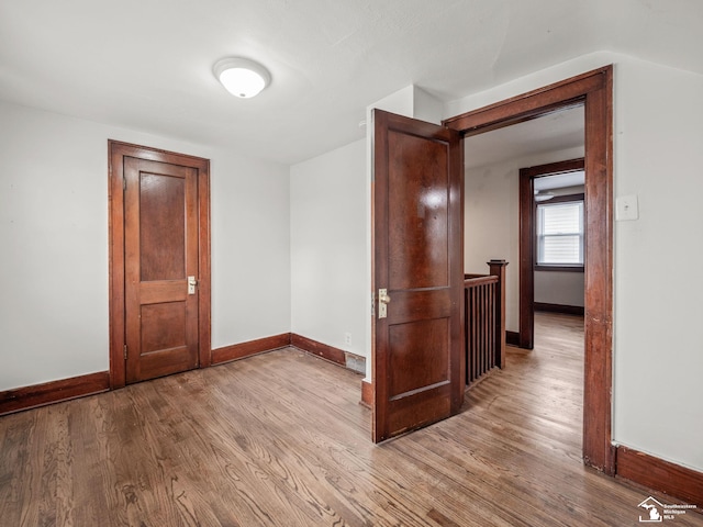 spare room with baseboards and wood finished floors