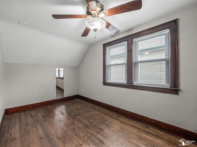 additional living space with vaulted ceiling, dark wood finished floors, a wealth of natural light, and baseboards