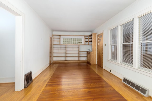 spare room with light wood-type flooring, visible vents, and baseboards