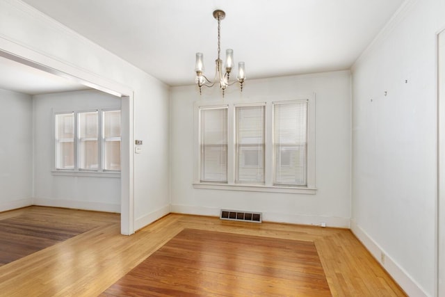 unfurnished dining area featuring baseboards, visible vents, a chandelier, and wood finished floors