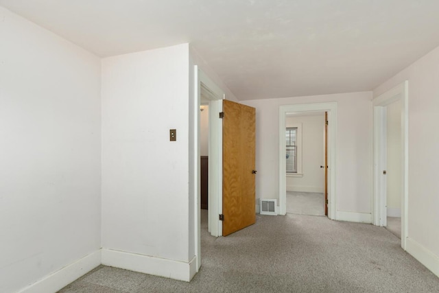 unfurnished room featuring visible vents, light carpet, and baseboards