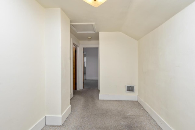 unfurnished room with carpet flooring, visible vents, baseboards, vaulted ceiling, and attic access