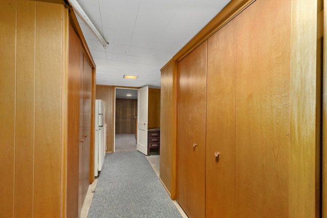 hall featuring light carpet and wood walls