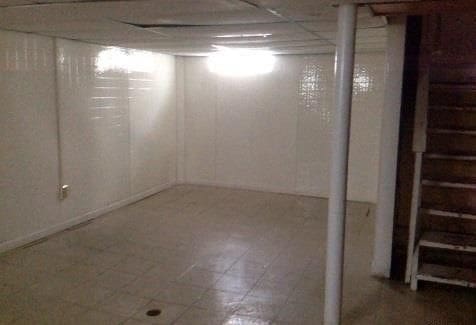 finished basement featuring stairs, a paneled ceiling, and tile patterned floors