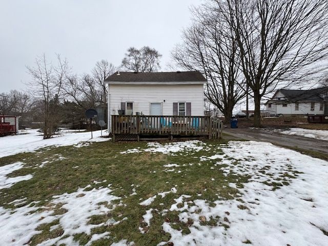 snow covered rear of property with a wooden deck