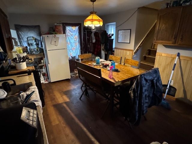 dining space with a wainscoted wall, stairs, and dark wood-style flooring