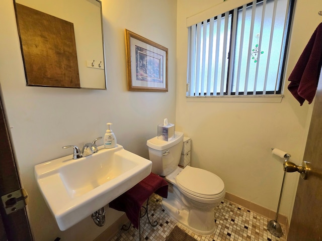 bathroom featuring baseboards, a sink, toilet, and tile patterned floors