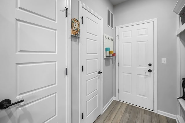 doorway with visible vents, wood finished floors, and baseboards