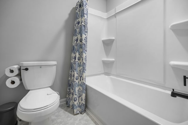 bathroom featuring toilet, baseboards, and shower / tub combo with curtain